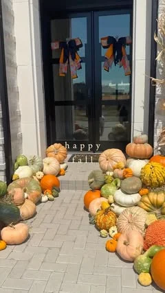 Pumpkins massed at a black double door with bows